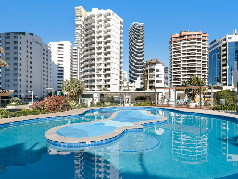 Outdoor pool area at ULTIQA Points North surrounded by palm trees and sun loungers.