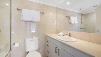 Spacious bathroom with vanity and mirrored cabinetry at ULTIQA Beach Haven on Broadbeach.