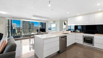Modern white kitchen with island bench at ULTIQA Beach Haven on Broadbeach.