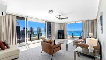 Spacious living room with leather furniture and a view of Gold Coast shore line at ULTIQA Beach Haven on Broadbeach.