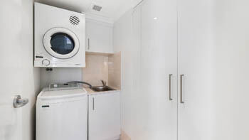Laundry room with new washing machine and dryer at an apartment at ULTIQA Beach Haven on Broadbeach.