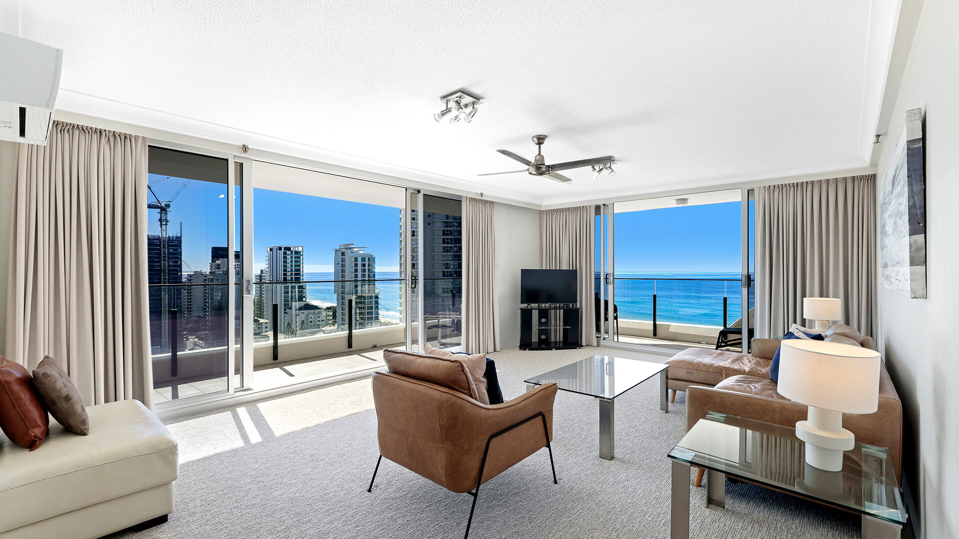 Spacious living room with leather furniture and a view of Gold Coast shore line at ULTIQA Beach Haven on Broadbeach.