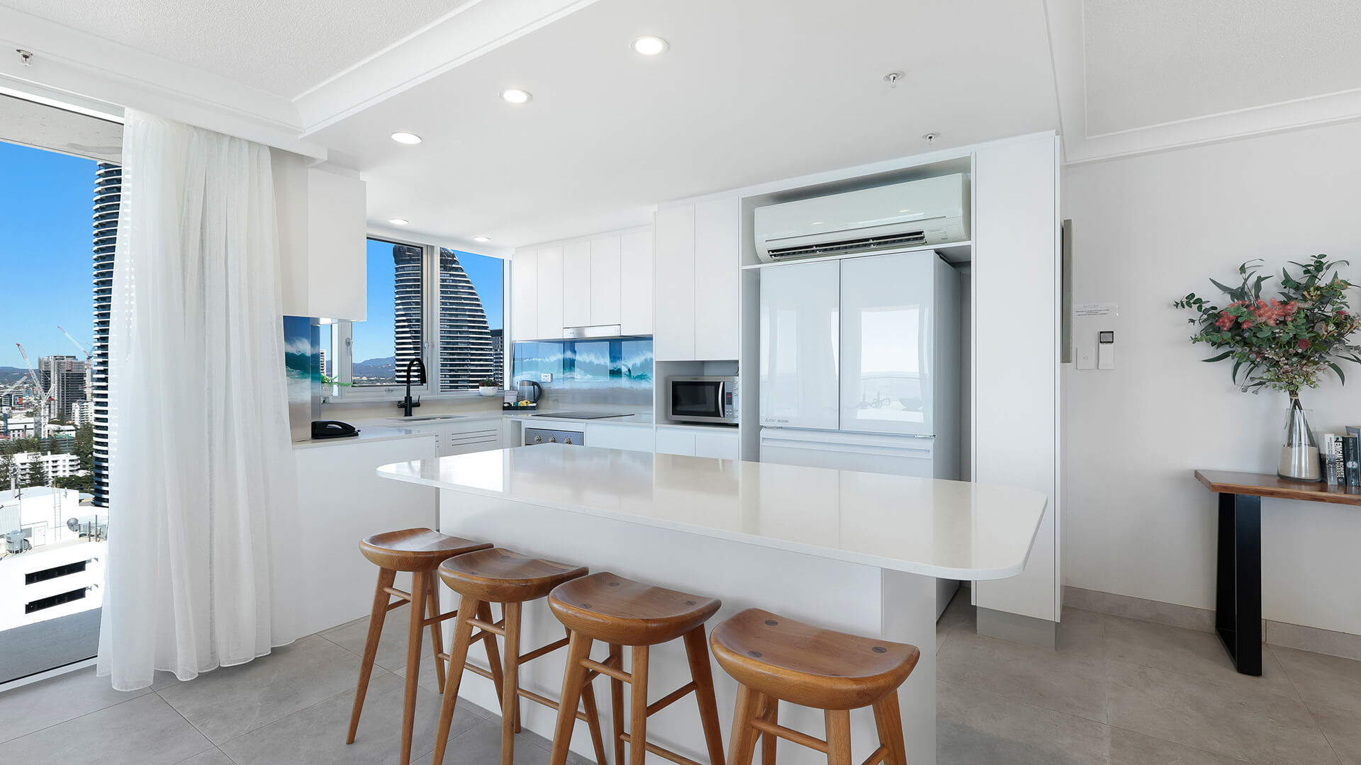 Kitchen island with bar stools and modern appliances at ULTIQA Beach Haven on Broadbeach, Surfers Paradise.