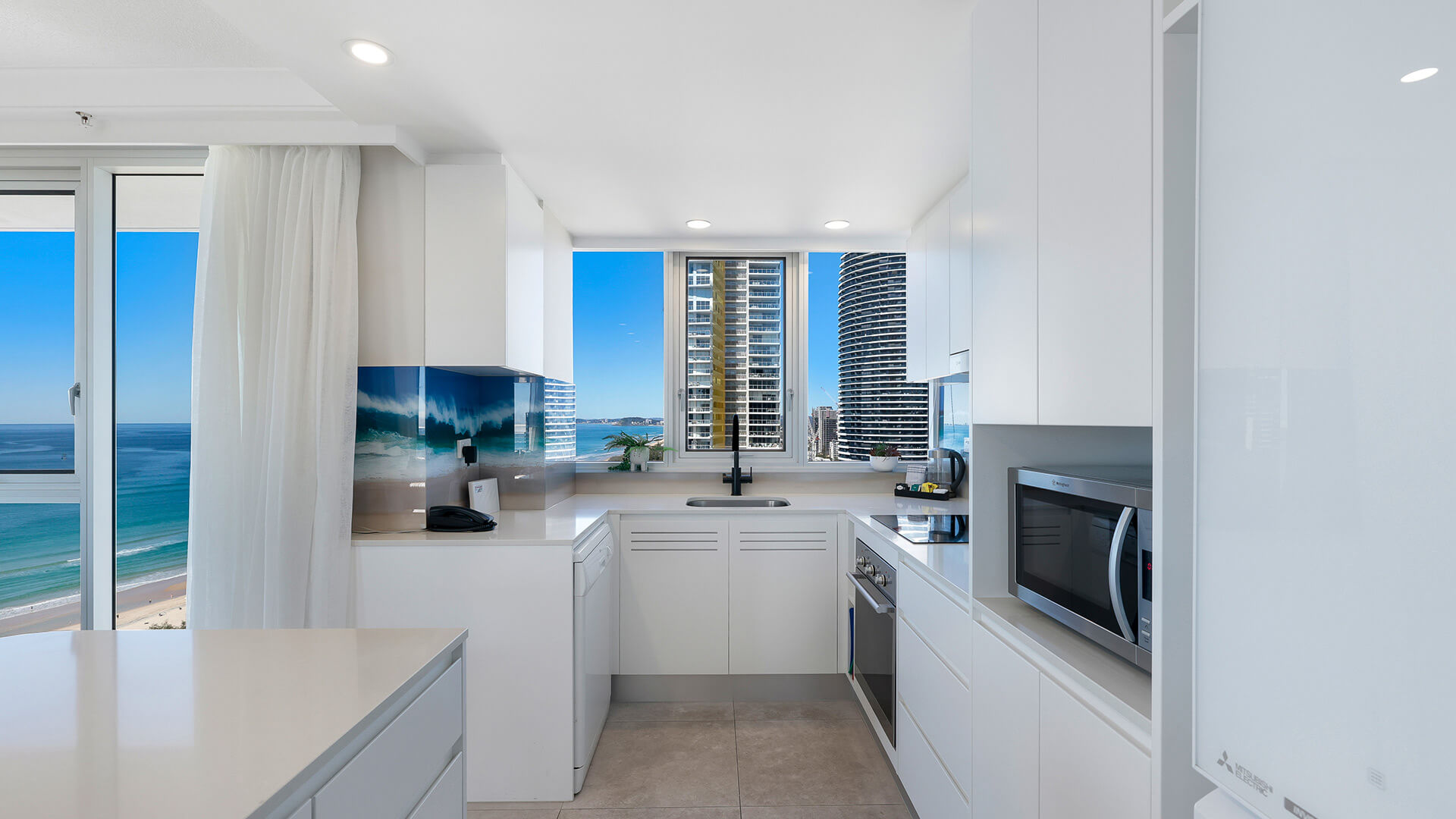 Sleek kitchen with sink window and city outlook at ULTIQA Beach Haven on Broadbeach, Gold Coast accommodation.