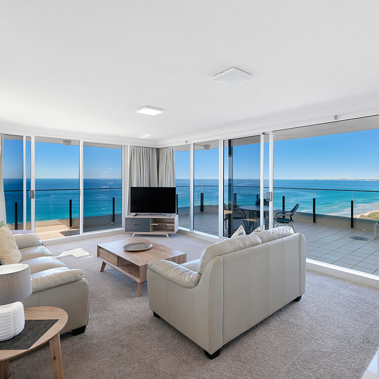 Ocean-view balcony at ULTIQA Points North Coolangatta with outdoor seating overlooking the beach, coastline, and sparkling turquoise water under a clear blue sky.