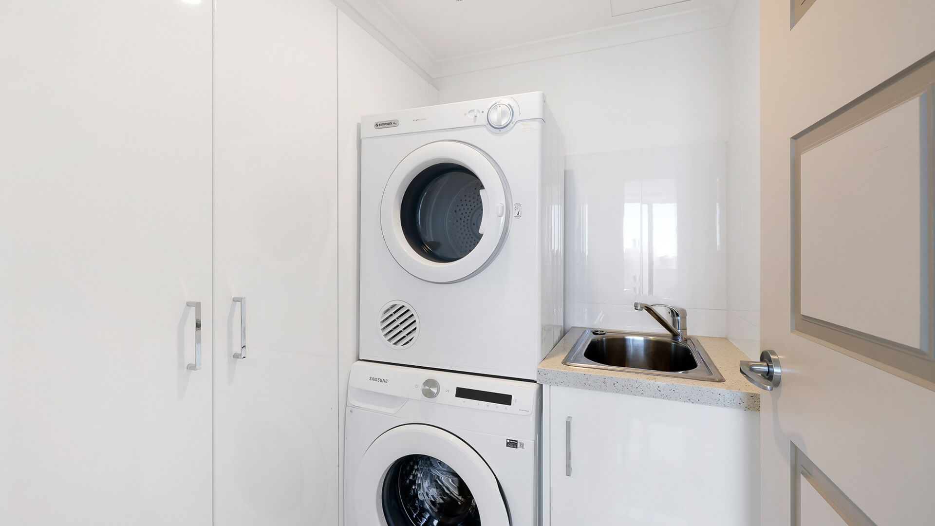 Fully equipped laundry in the Sub Penthouse at ULTIQA Beach Haven on Broadbeach, featuring a washer, dryer, and sink.
